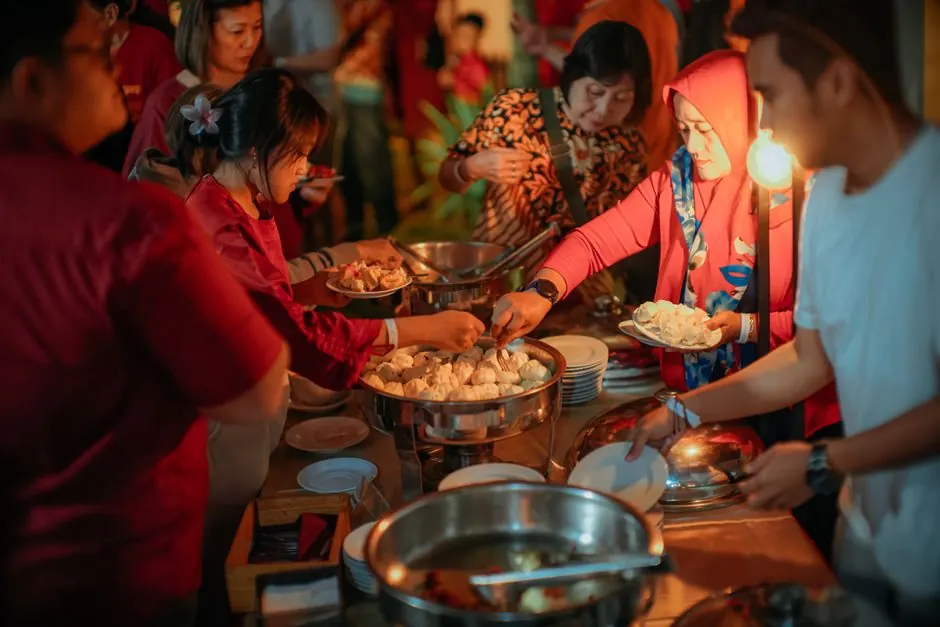 A group of adults engaging in a lively buffet dinner event. Warm lighting and diverse participation.