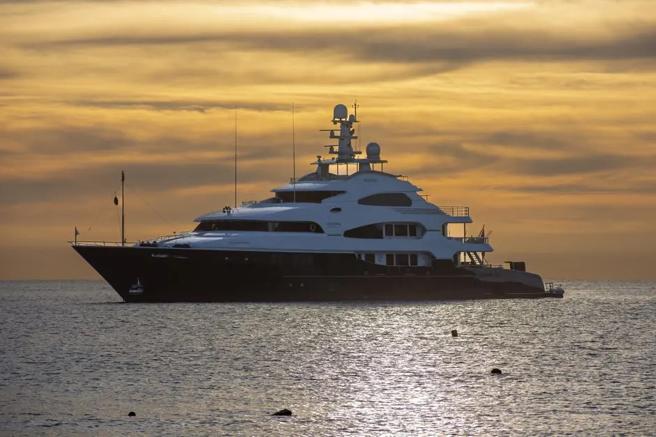 Stunning view of a luxury yacht sailing at sunset in Cabo San Lucas, Mexico's tranquil waters.